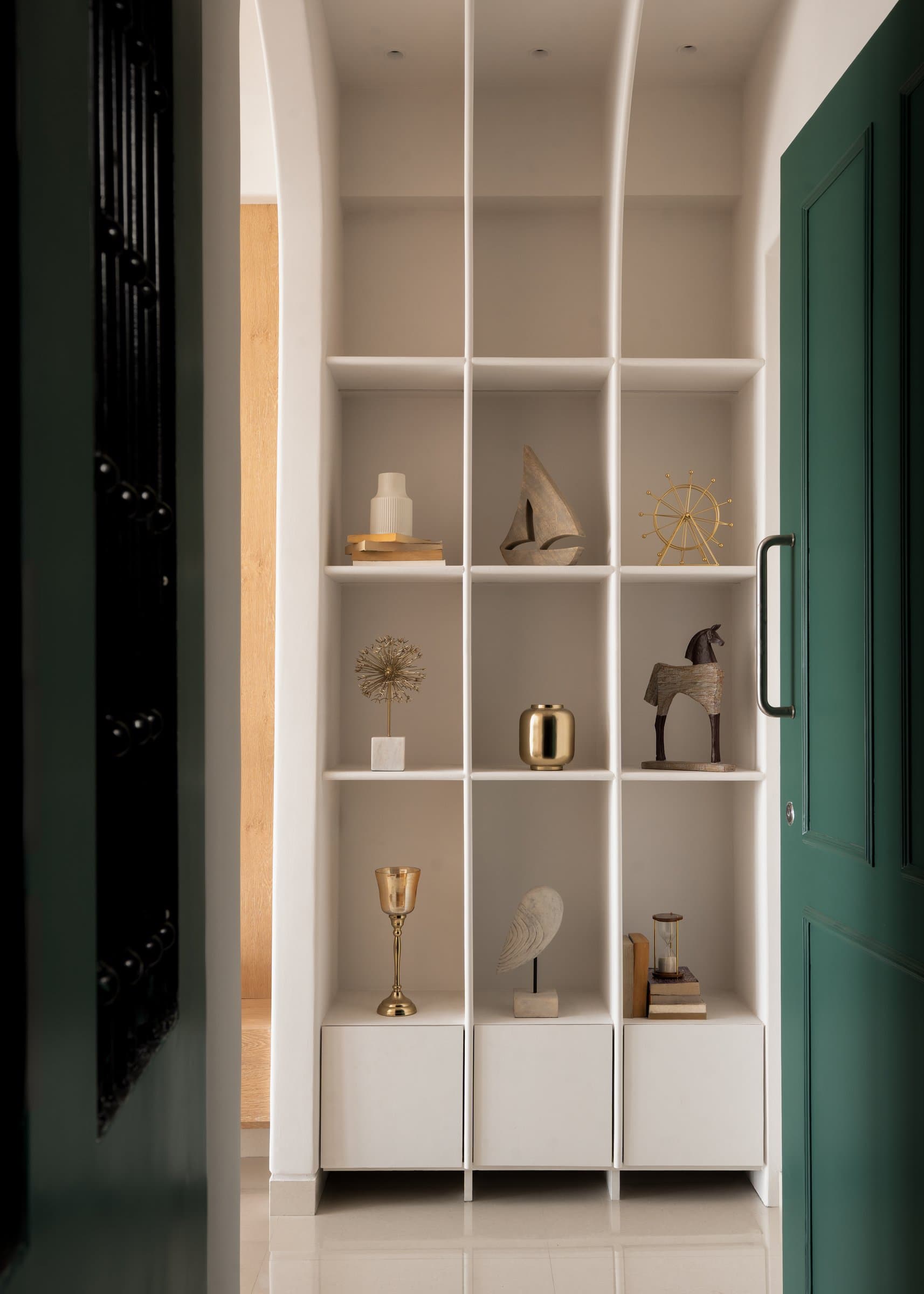The arched display niche just inside the entry, its collected objects setting the vintage-modern dialogue in miniature