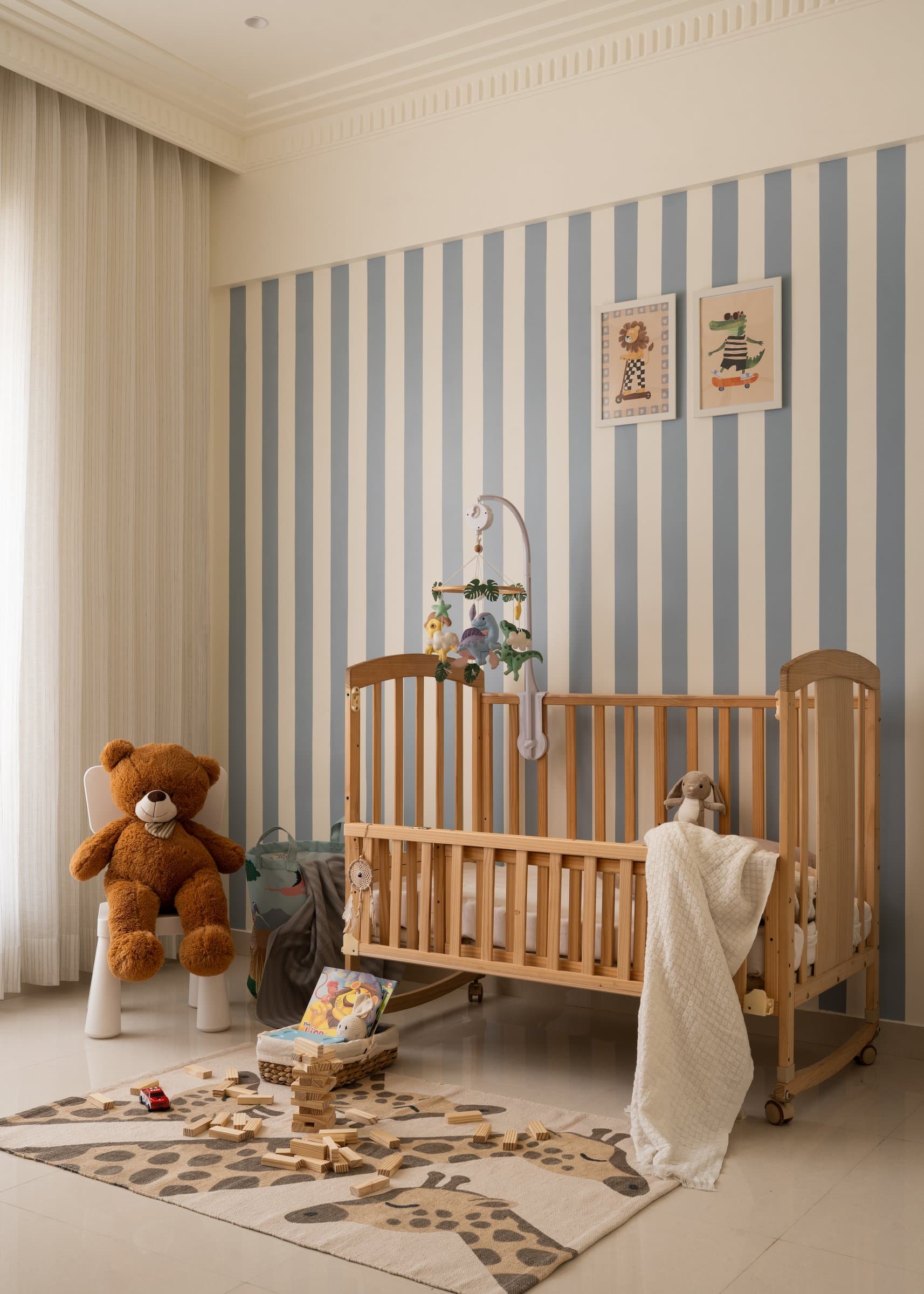 The nursery, wrapped in blue and cream vertical stripes, accommodating the family's next chapter