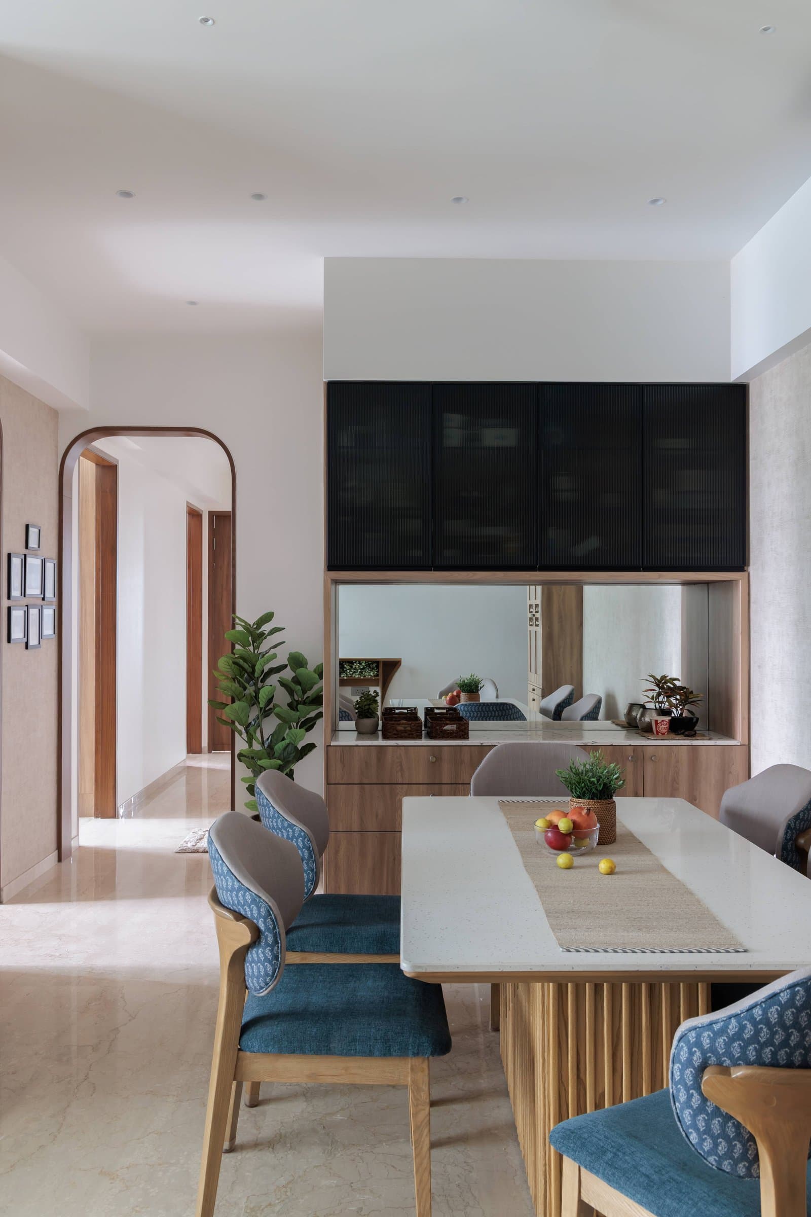 The dining area, centred on a fluted-base table and ringed by chairs with block-printed inner backs