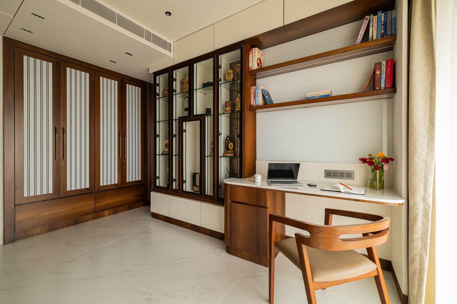 The study, its warm wood-framed wardrobes and metal-framed display cabinet giving the room its tactile register