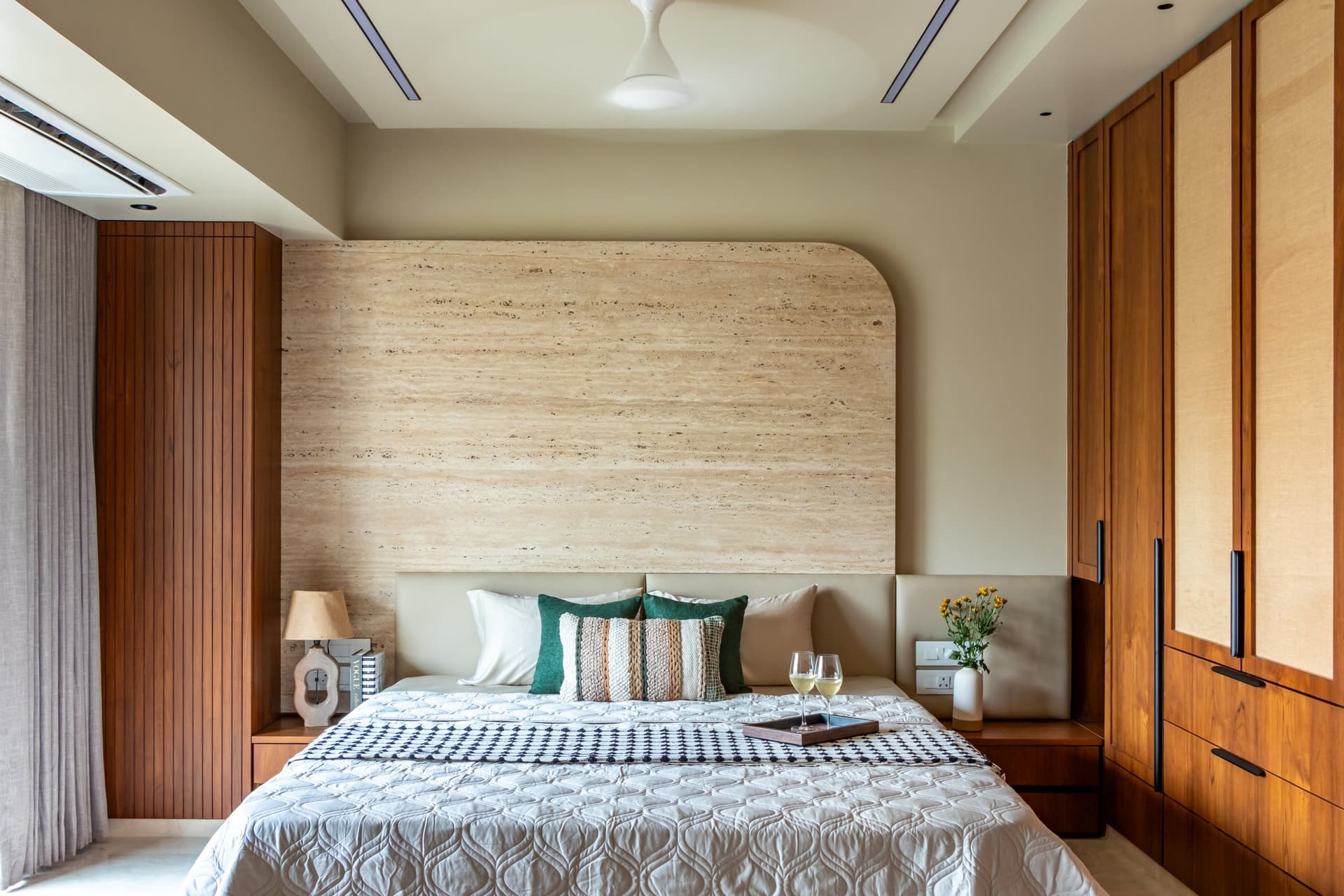 The principal bedroom, where a softly arched travertine feature wall sets the tonal key