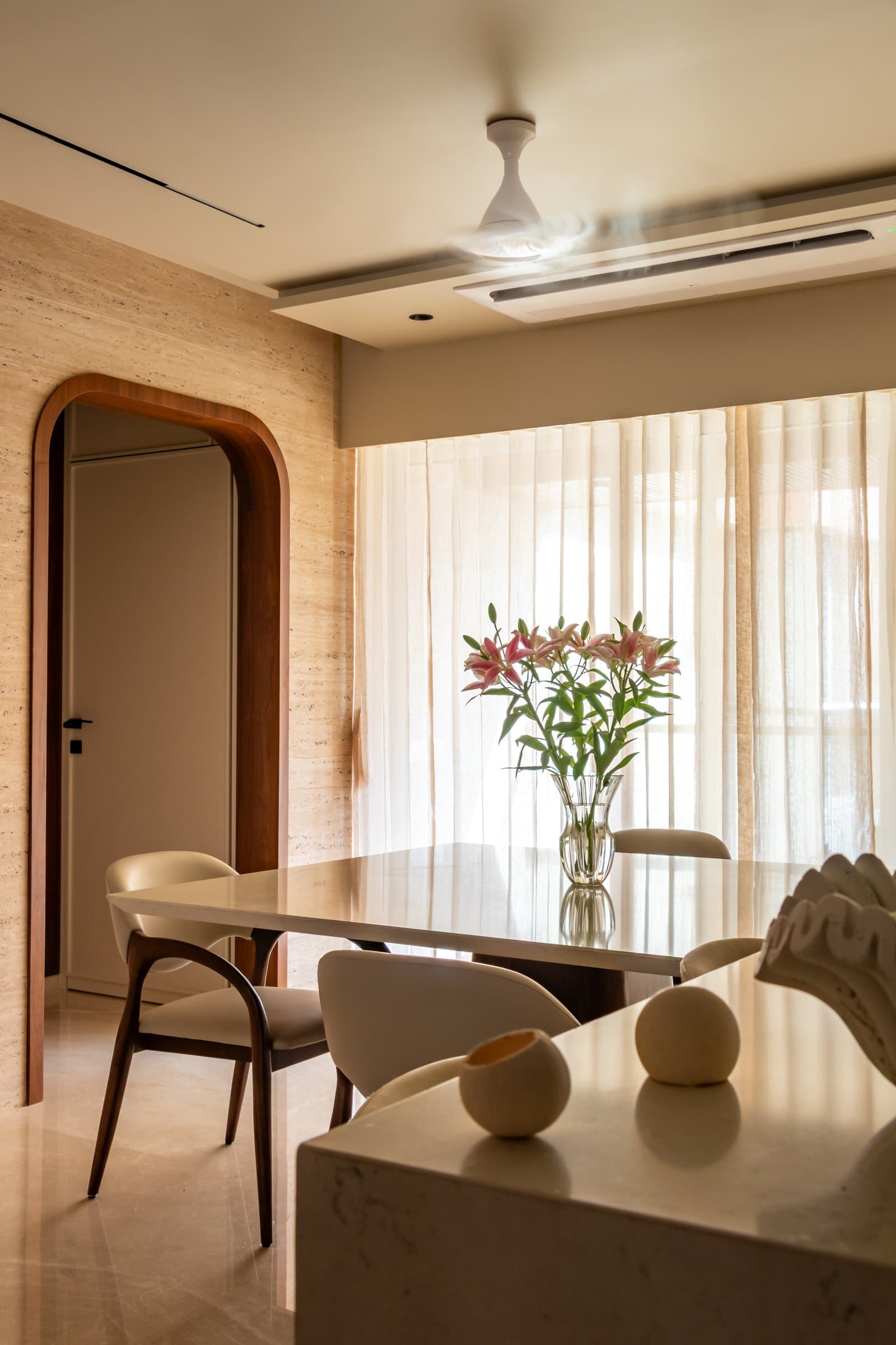 A walnut-framed arched doorway marks the passage from the dining area towards the bedrooms
