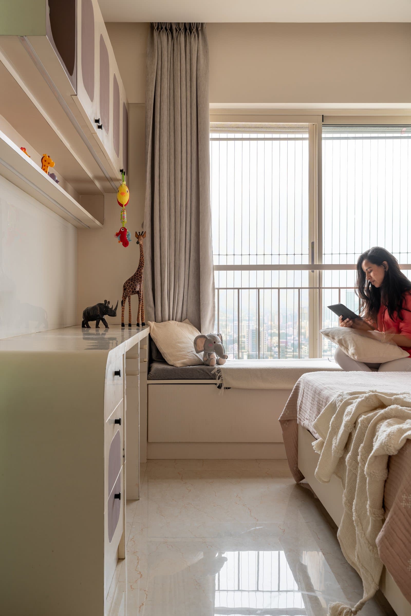The children's room, with a window seat, low chest and tonal upper cabinetry framing a tall city window