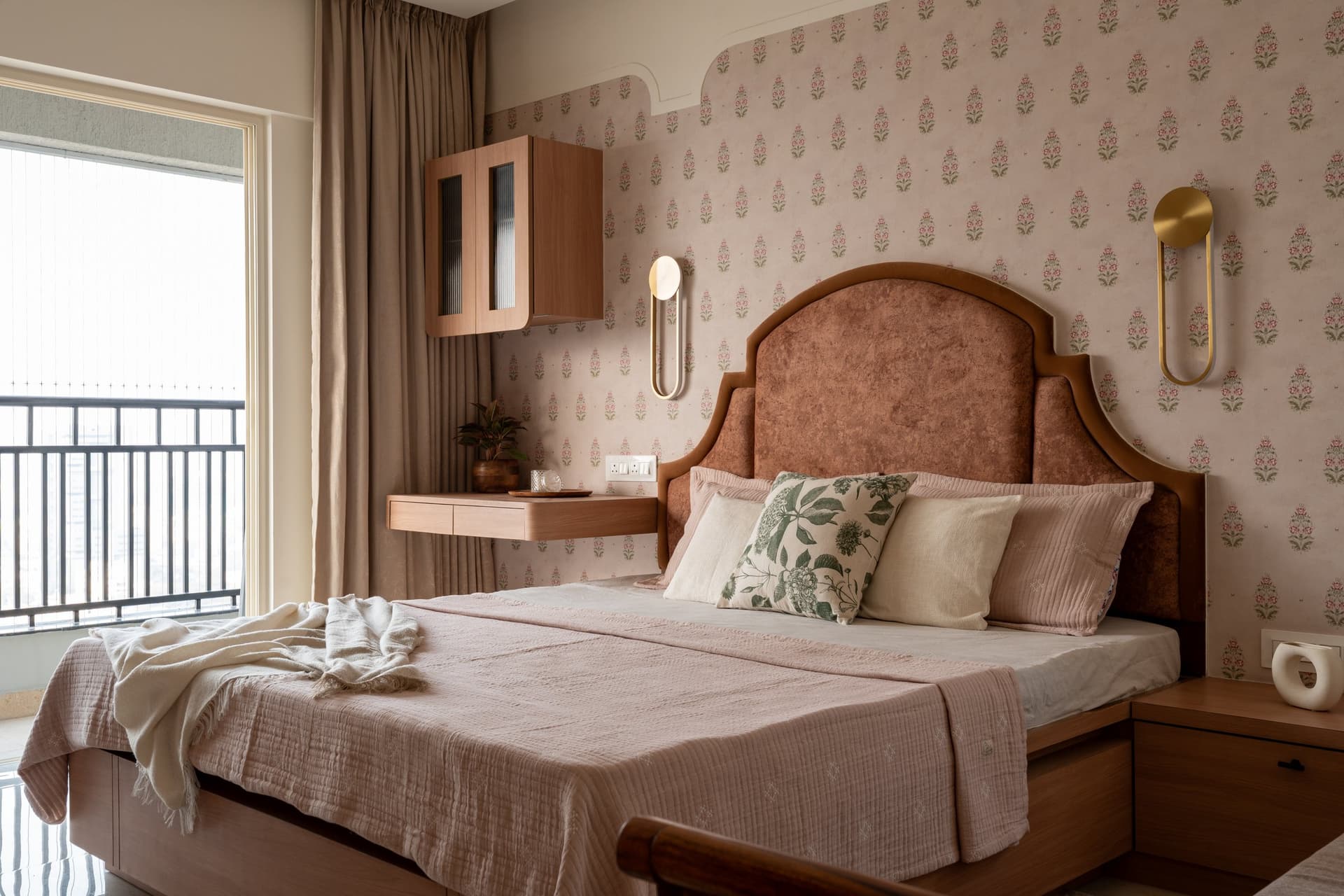 The master bedroom, with an arched upholstered headboard set against a small-motif wallpapered wall