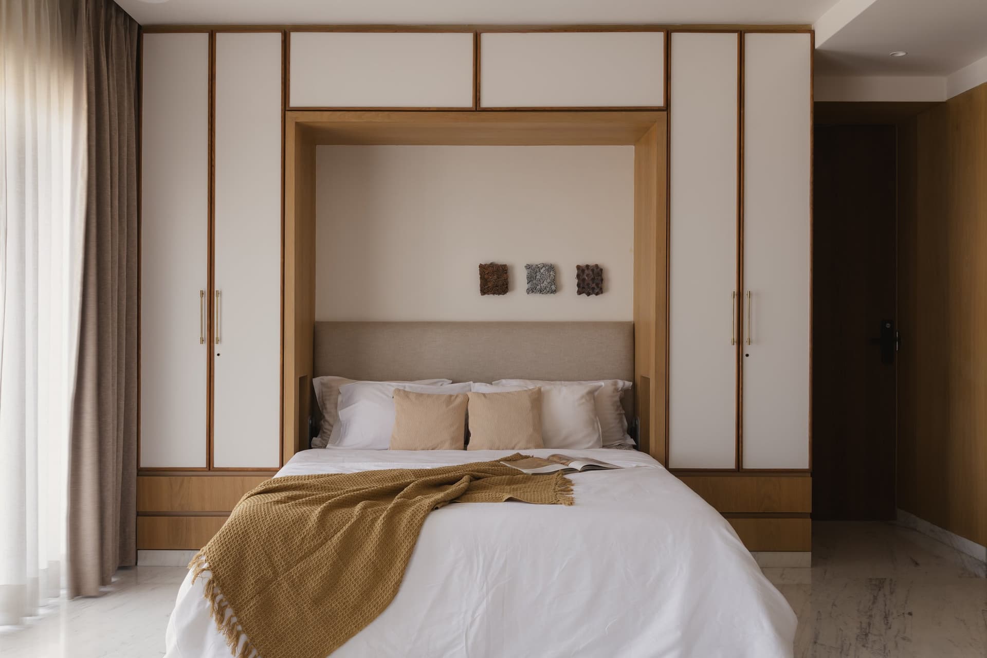 The primary bedroom, with its oak-framed bed niche flanked by ivory wardrobe panels