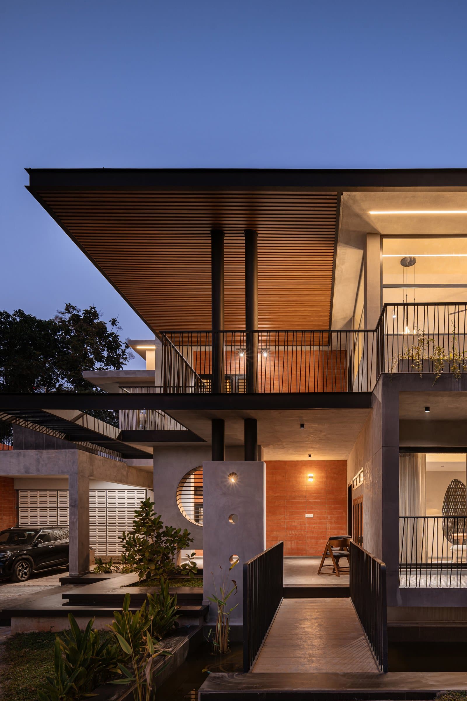 The approach at dusk, with a slim bridge crossing the fish pond toward the formal living room