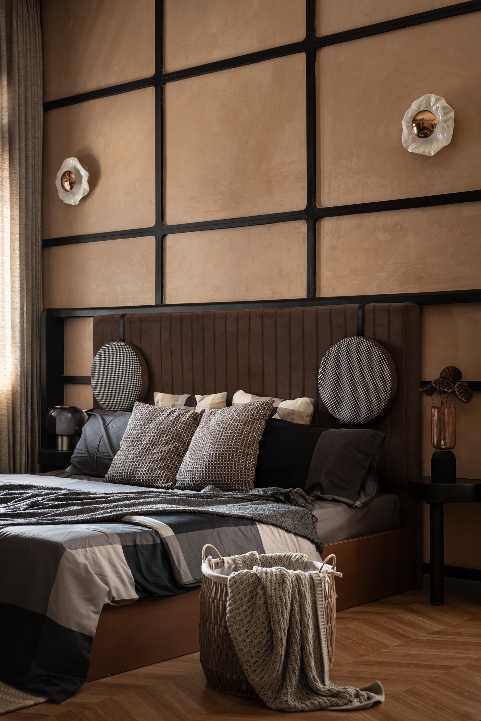 The primary bedroom, with leather-finished panels framed in blackened steel behind a channel-tufted velvet headboard