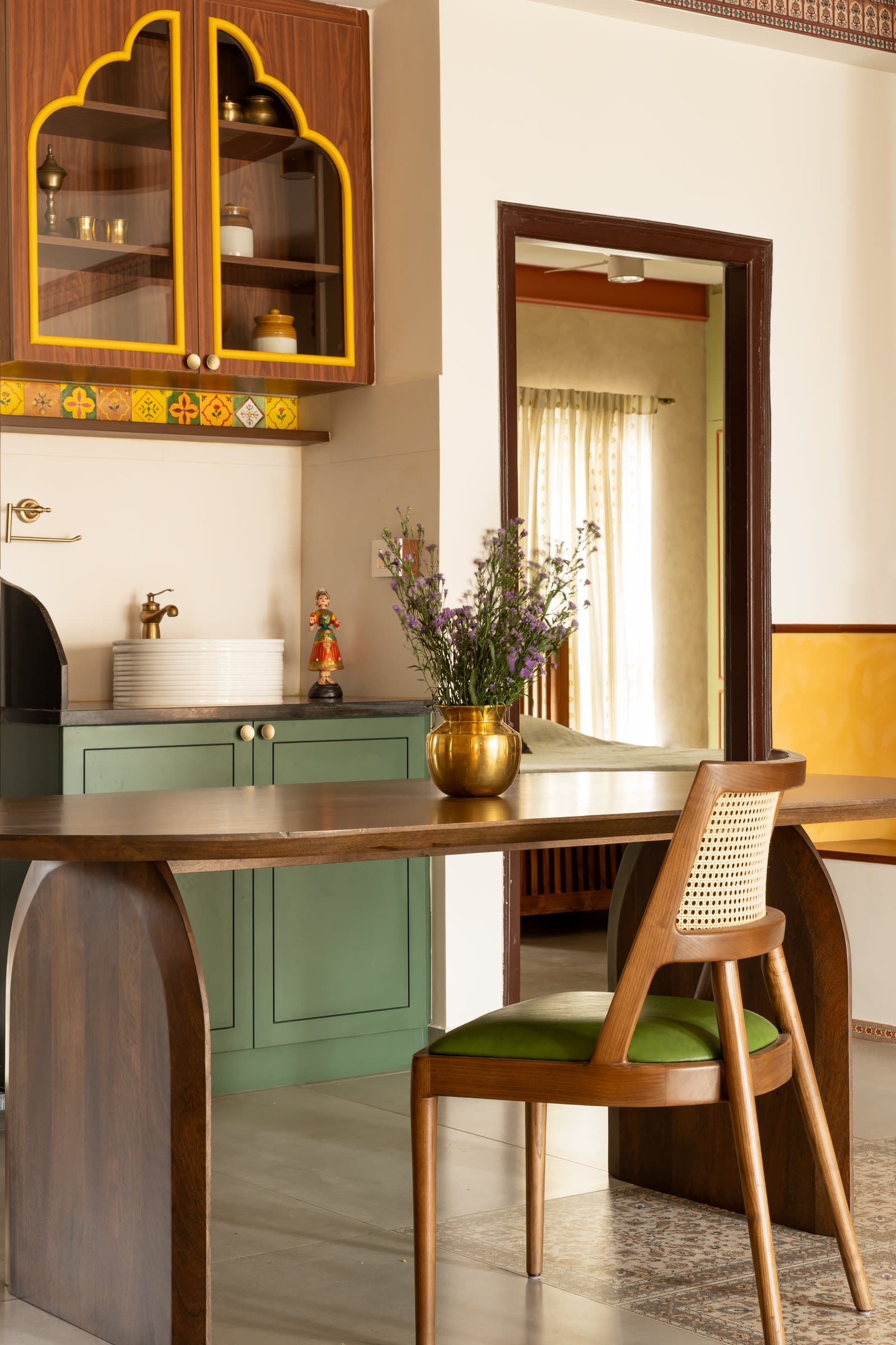 The handwash unit in sage green cabinetry, with its arched upper cabinet trimmed in yellow and a band of patterned tiles