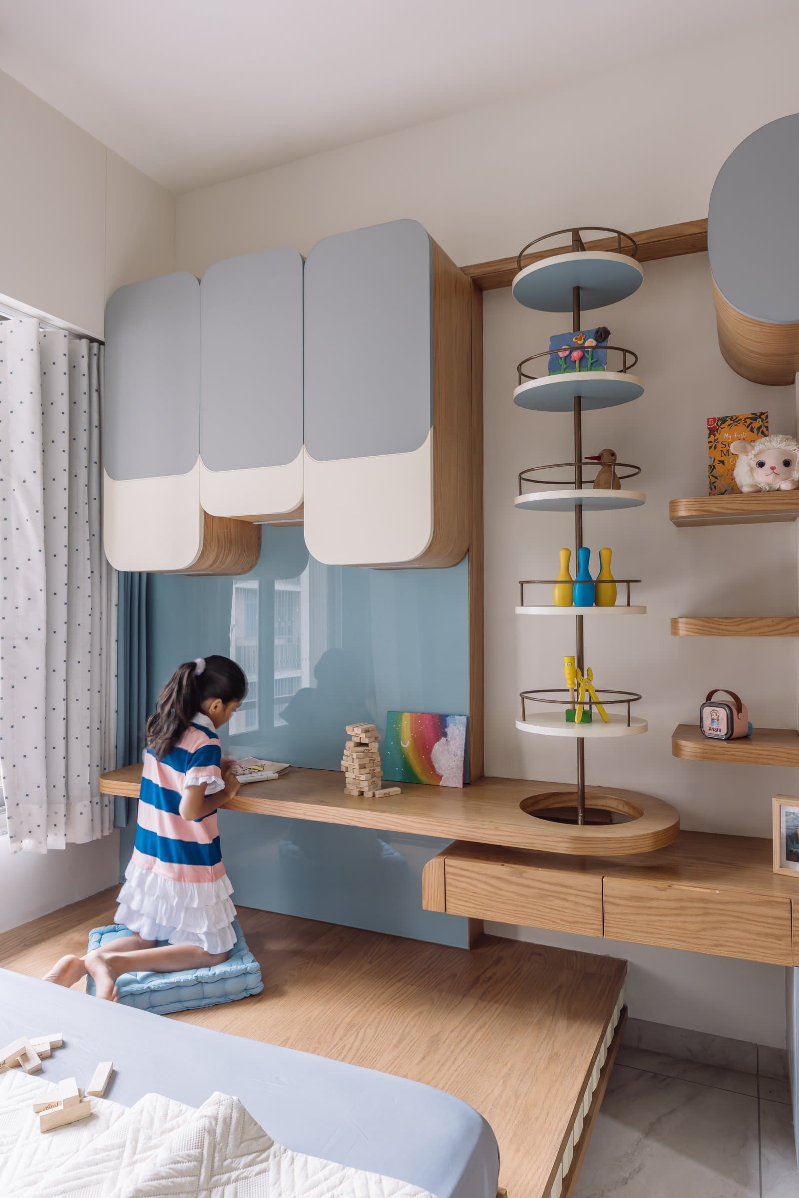 The desk and reflective blue panel in the children's room, where play, storage and study share one architectural vocabulary