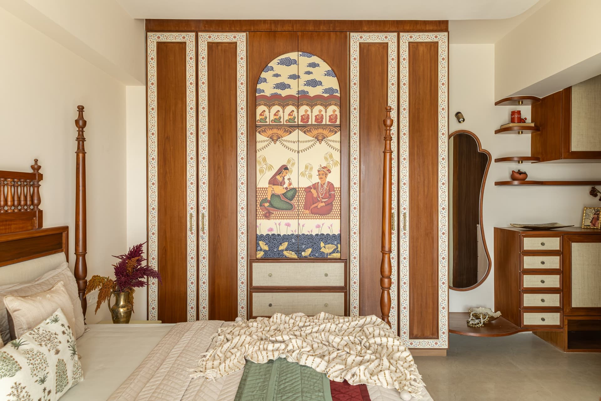 The wardrobe wall, where a Mughal-inspired painted panel is framed within an arched contour with woven-fronted drawers below