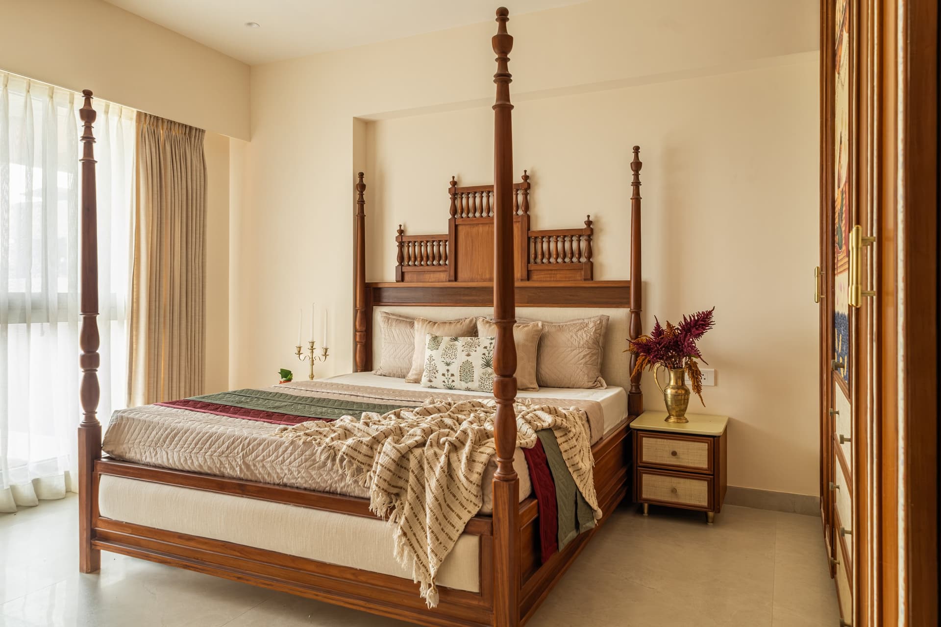 The primary bedroom, where a four-poster wooden bed with turned finials anchors the room against a quiet ivory backdrop