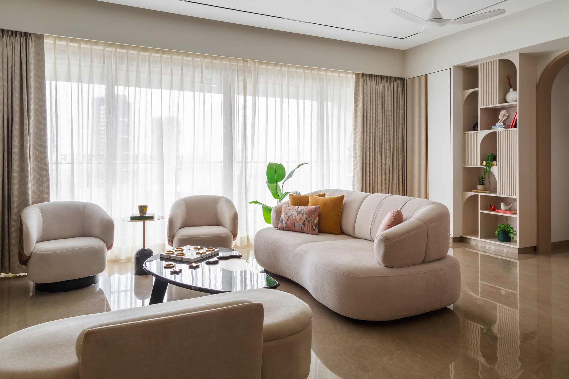 The living room, where curved silhouettes and sheer light carry the composition in place of hard geometry