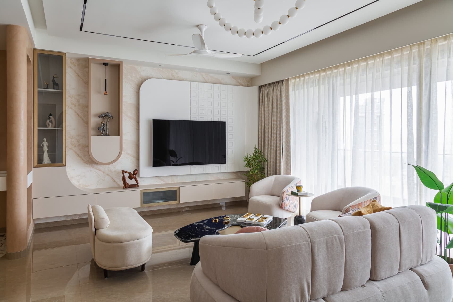 The media wall, layering veined stone with a textured gridded panel and a curved ivory frame cradling the television